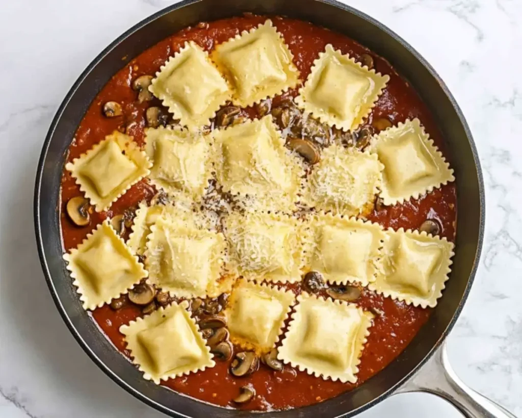 Cheese ravioli added to a skillet with a tomato mushroom sauce.