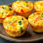 A mouthwatering image of egg muffins bursting with melted cheese, savory meat, and fresh vegetables, perfect for a nutritious breakfast.