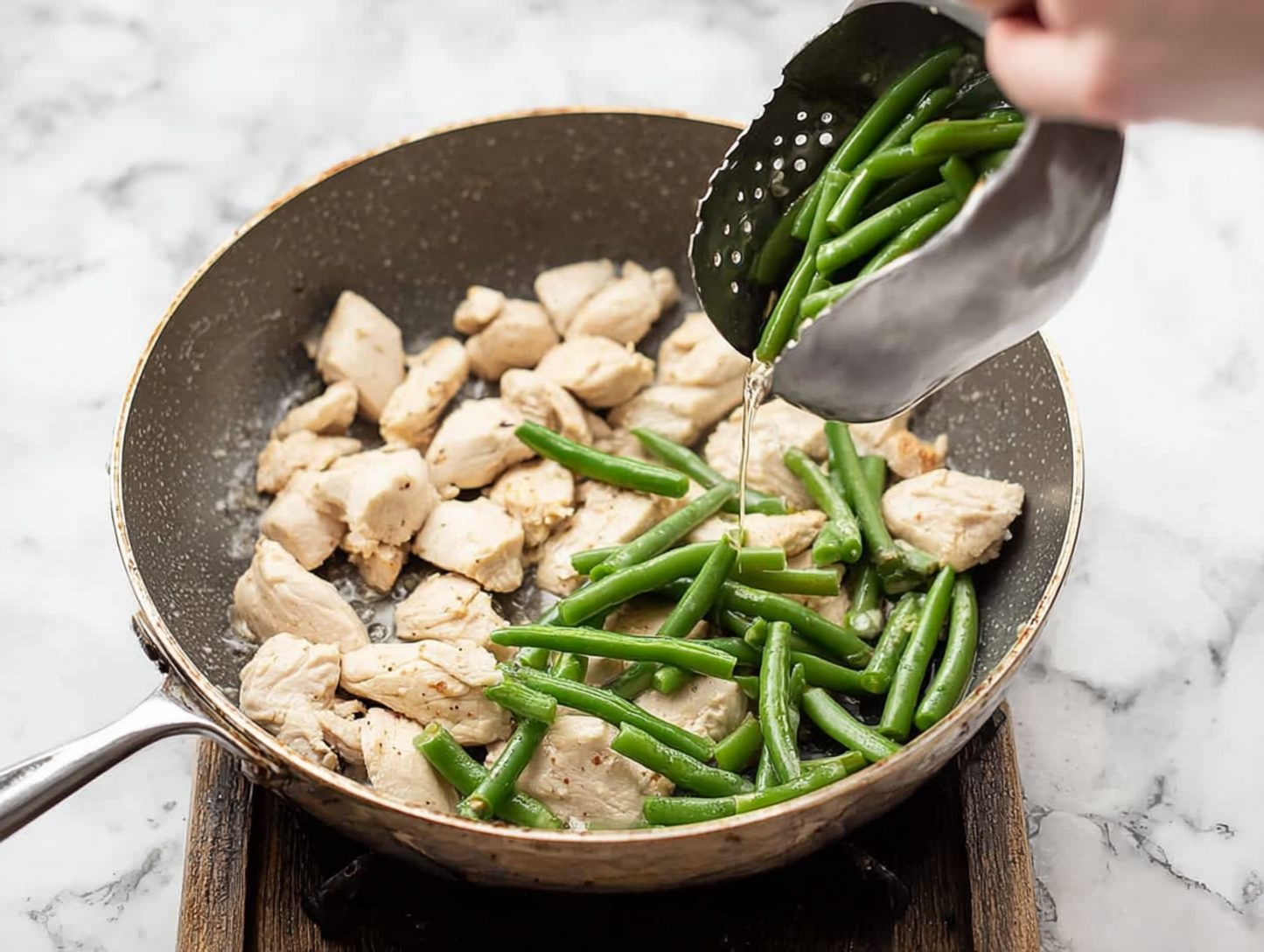 Chicken cooking with green beans added in skillet