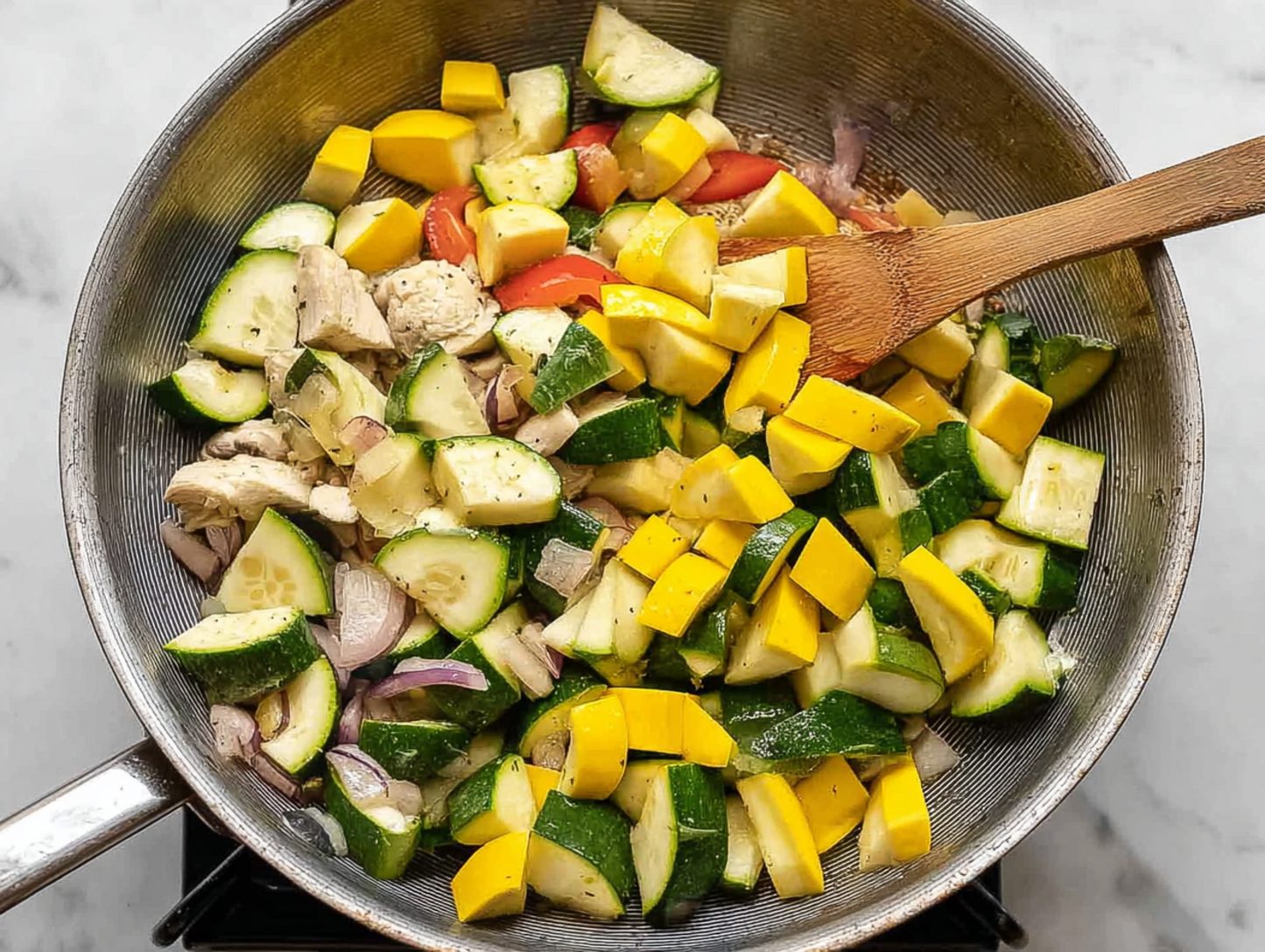 Skillet full of chicken and mixed vegetables including zucchini and squash