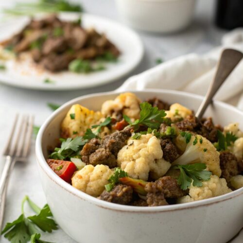 A delicious close-up of skillet keto beef and cauliflower, showing vibrant colors and fresh garnishes