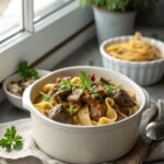 Finished Dutch Oven Beef Stroganoff served in a white bowl with fresh parsley garnish