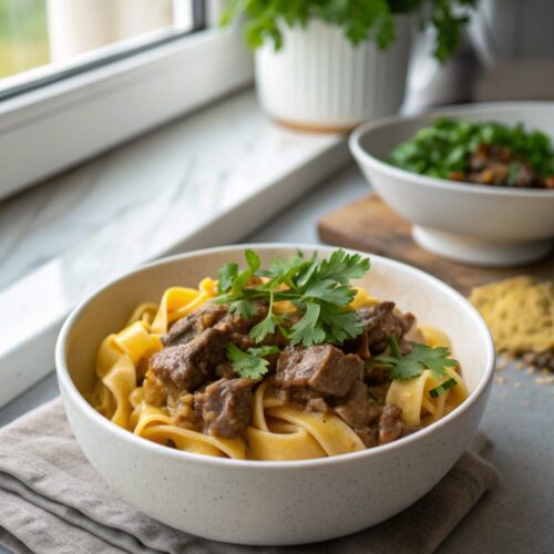 A serving of easy beef stroganoff garnished with parsley on a white plate.