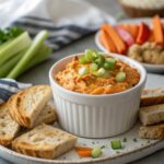 Delicious buffalo chicken dip, perfect for tailgates, served with garnishes.
