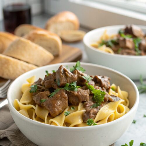 Rich and creamy featured image of slow cooked beef stroganoff topped with parsley.